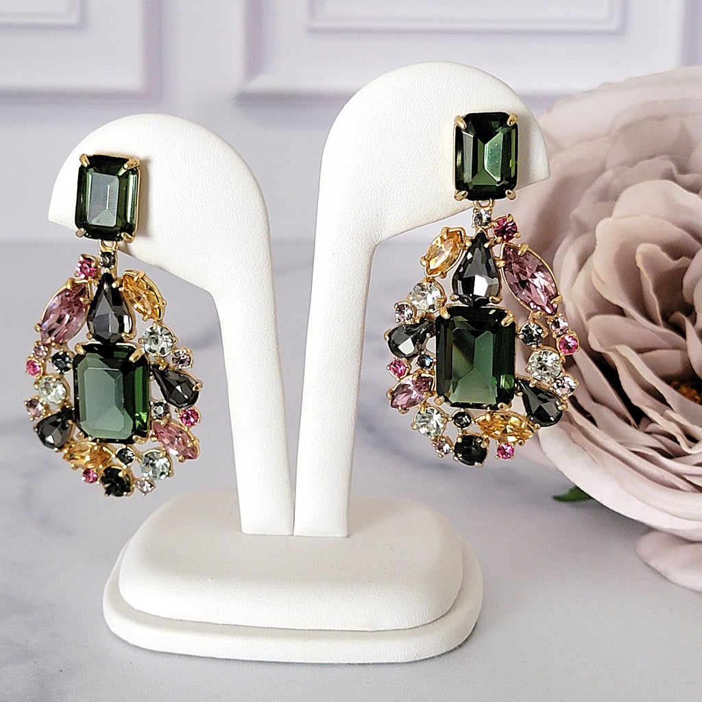 Green rhinestone dangle earrings on a display stand.