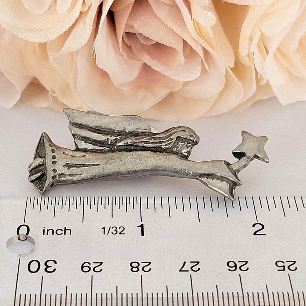 Angel pin next to a ruler.