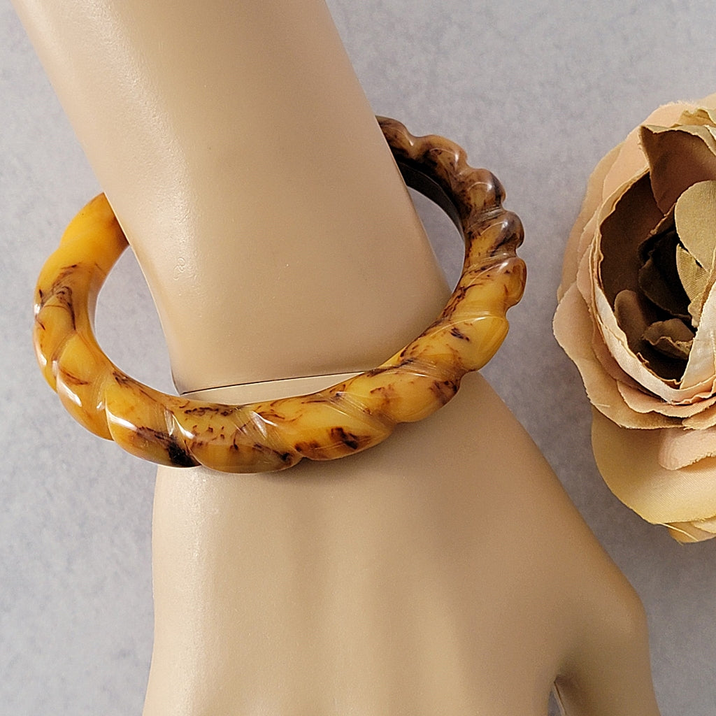 Yellow and brown Bakelite bracelet on wrist.