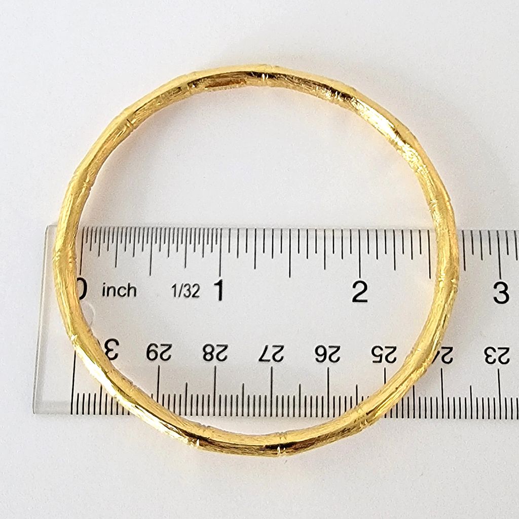 Gold tone bracelet on top of a ruler.