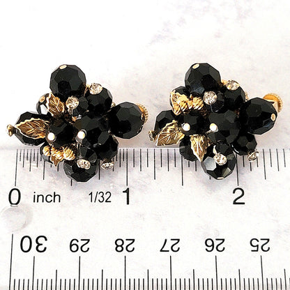 Black cluster earrings next to a ruler.