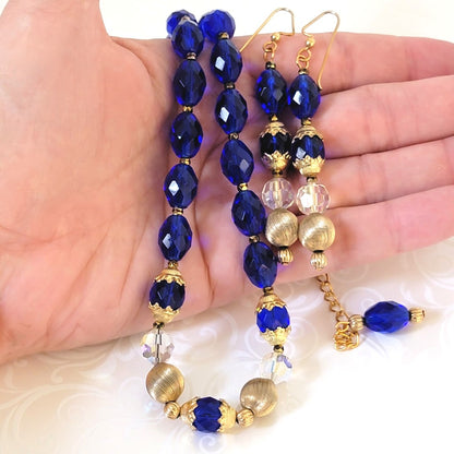 Vivid blue glass necklace and dangle earrings set, shown in hand, for size comparison.