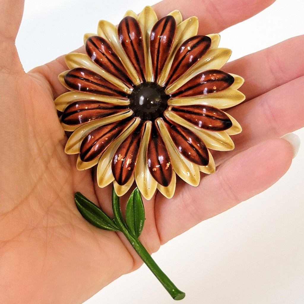 Big enamel flower pin in hand.