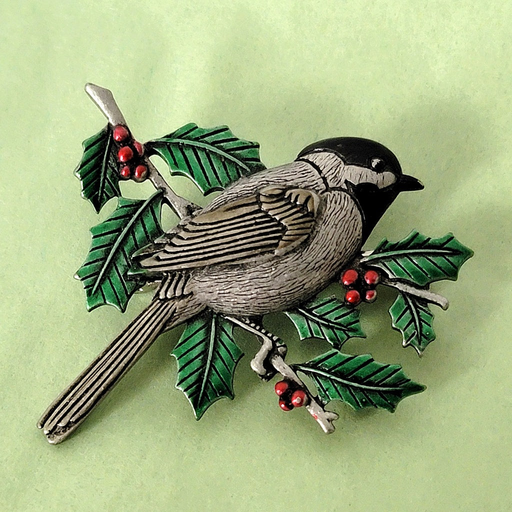 Chickadee brooch on a green background.