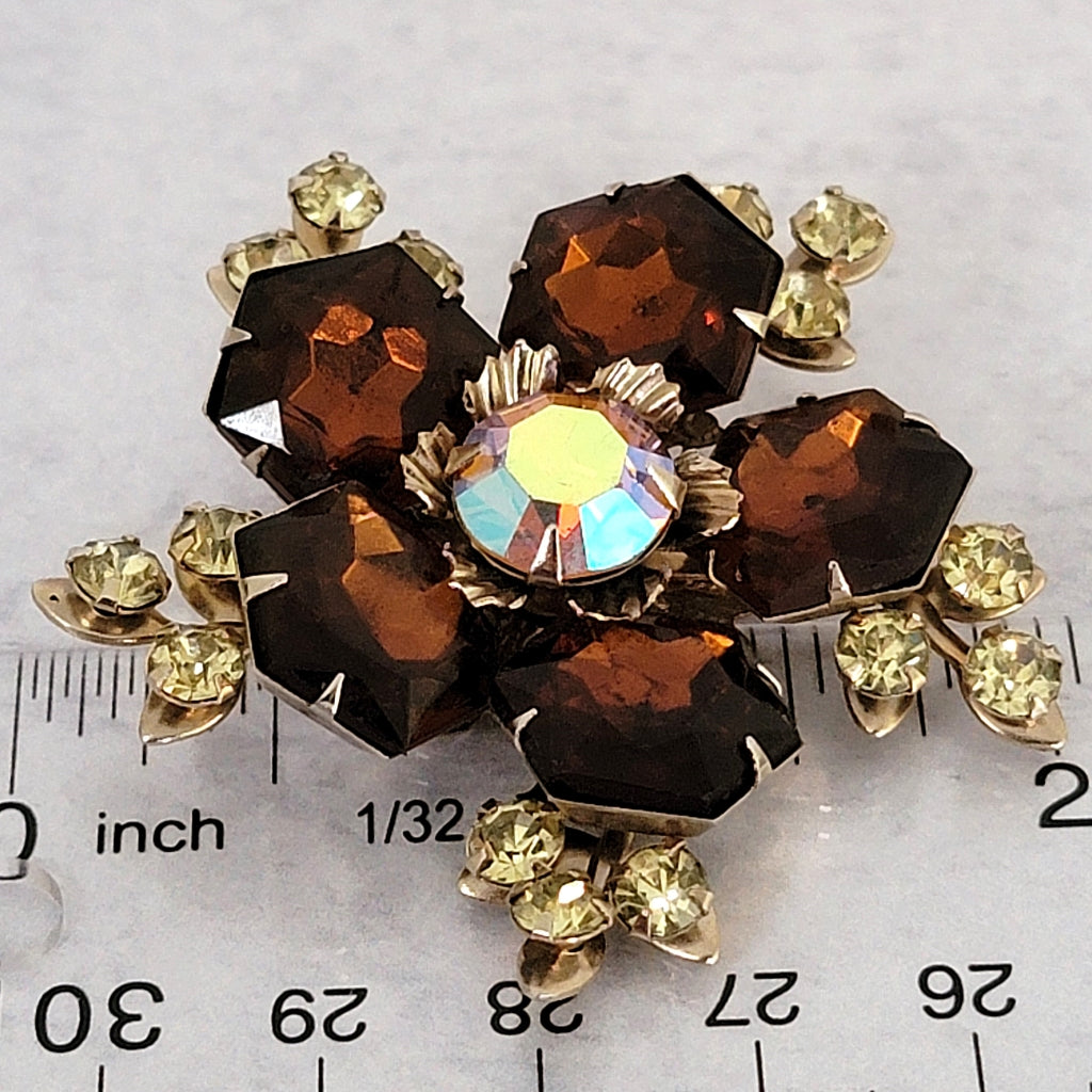 Brown rhinestone pin next to a ruler.