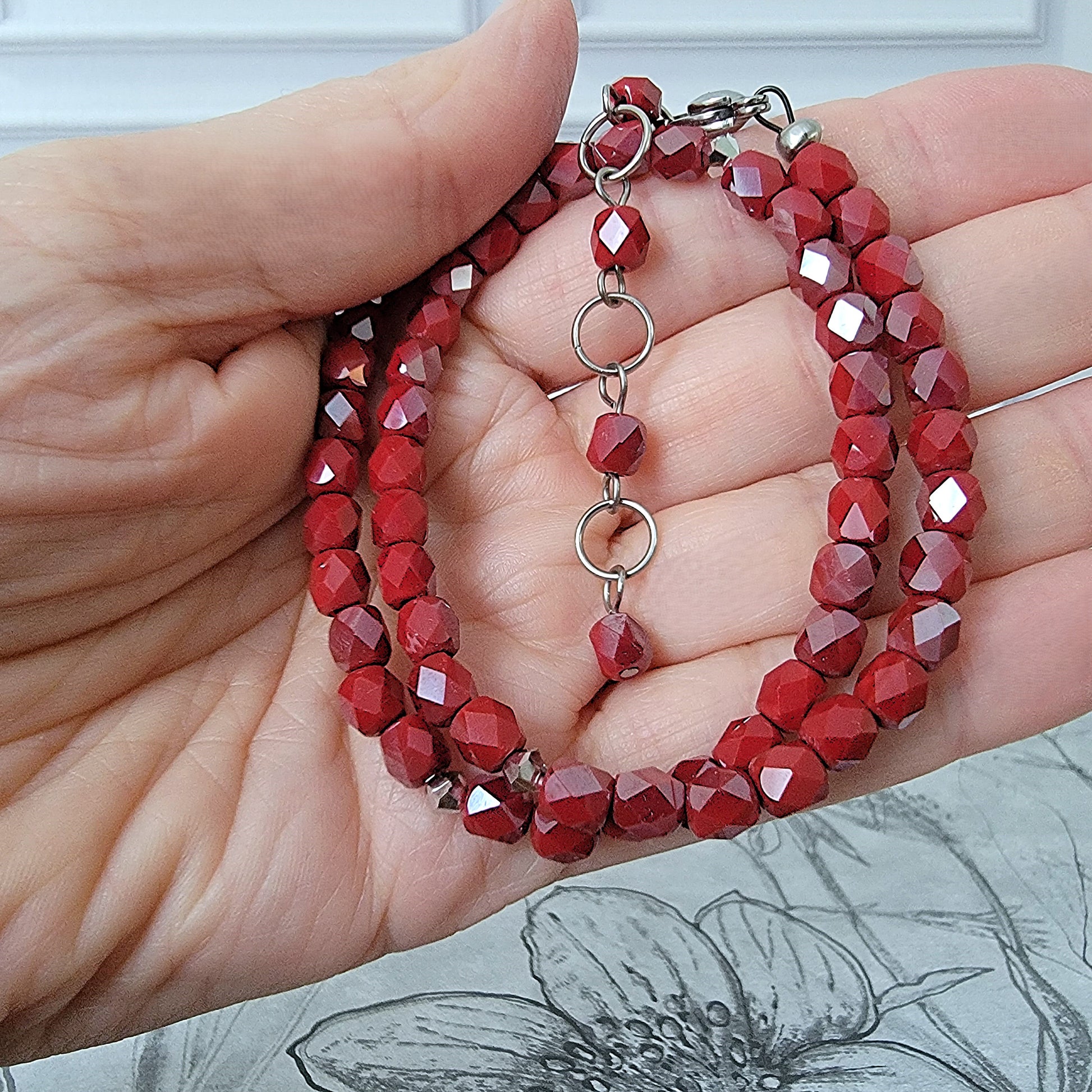 Red glass bead necklace in hand.