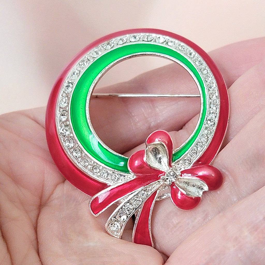 Red and green Christmas wreath pin in hand.