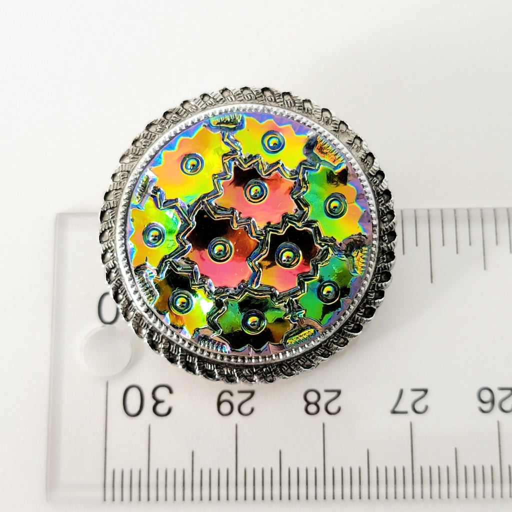 Vintage round floral scarf clip next to a ruler.