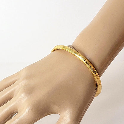 Gold tone bangle bracelet on wrist.