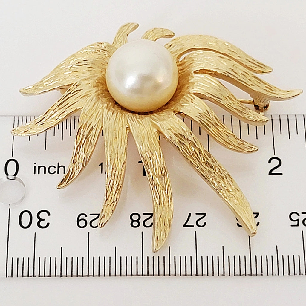 Vintage gold tone faux pearl flower pin next to a ruler.