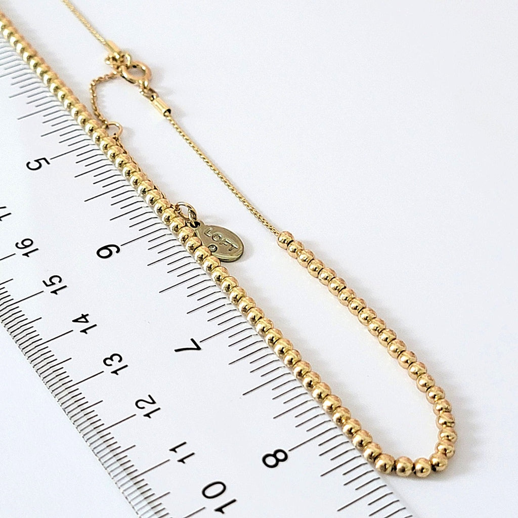 Small gold tone beads with a ruler.