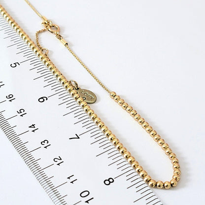 Small gold tone beads with a ruler.