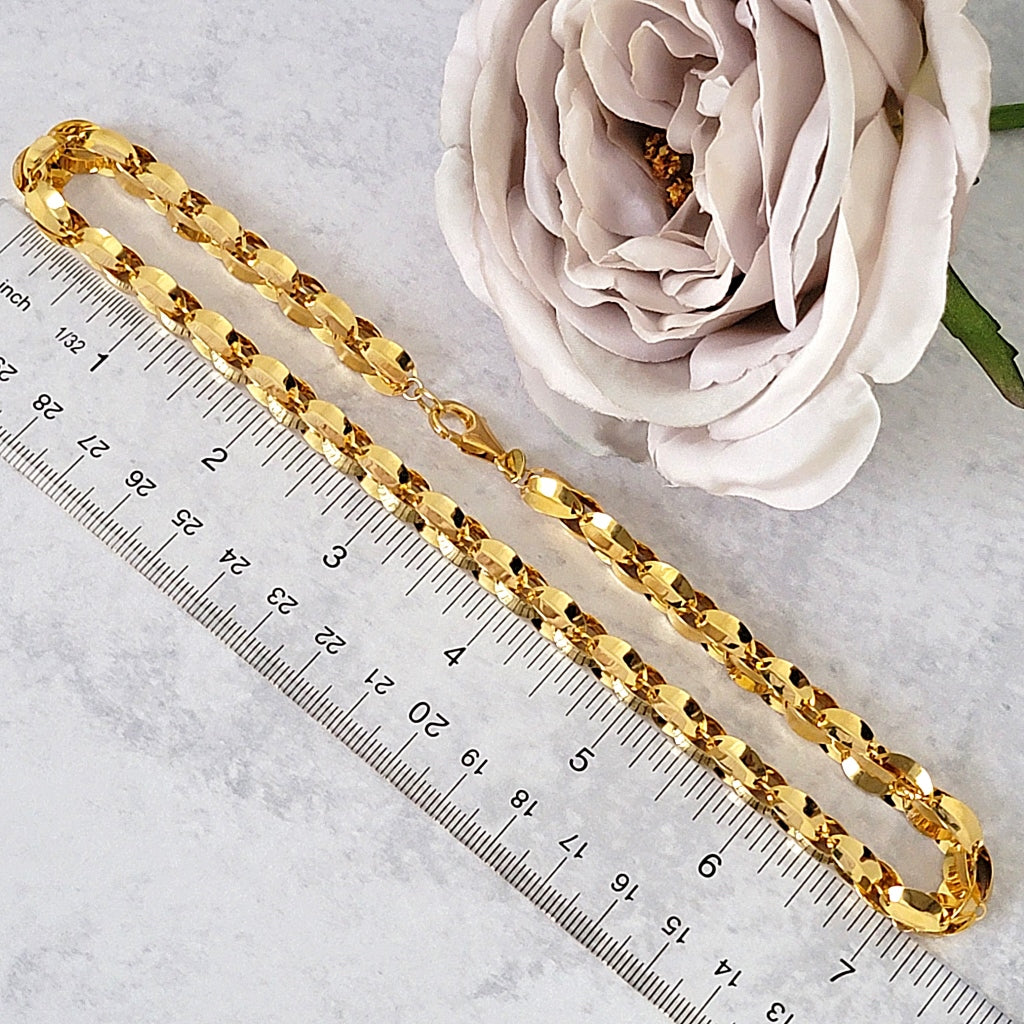 Gold tone chain necklace next to a ruler.