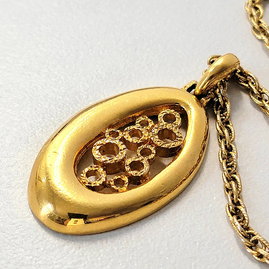 Modernist gold tone pendant with circles inside an oval design.