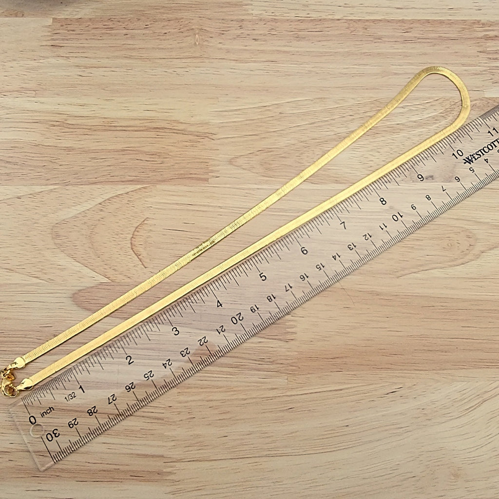 Gold tone chain next to a ruler.