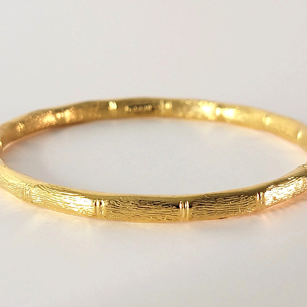 Textured detail on a gold tone bracelet.