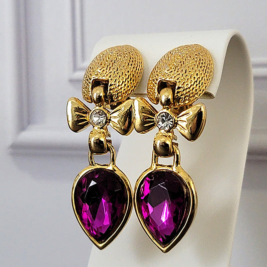 Purple glass dangle earrings with bows.