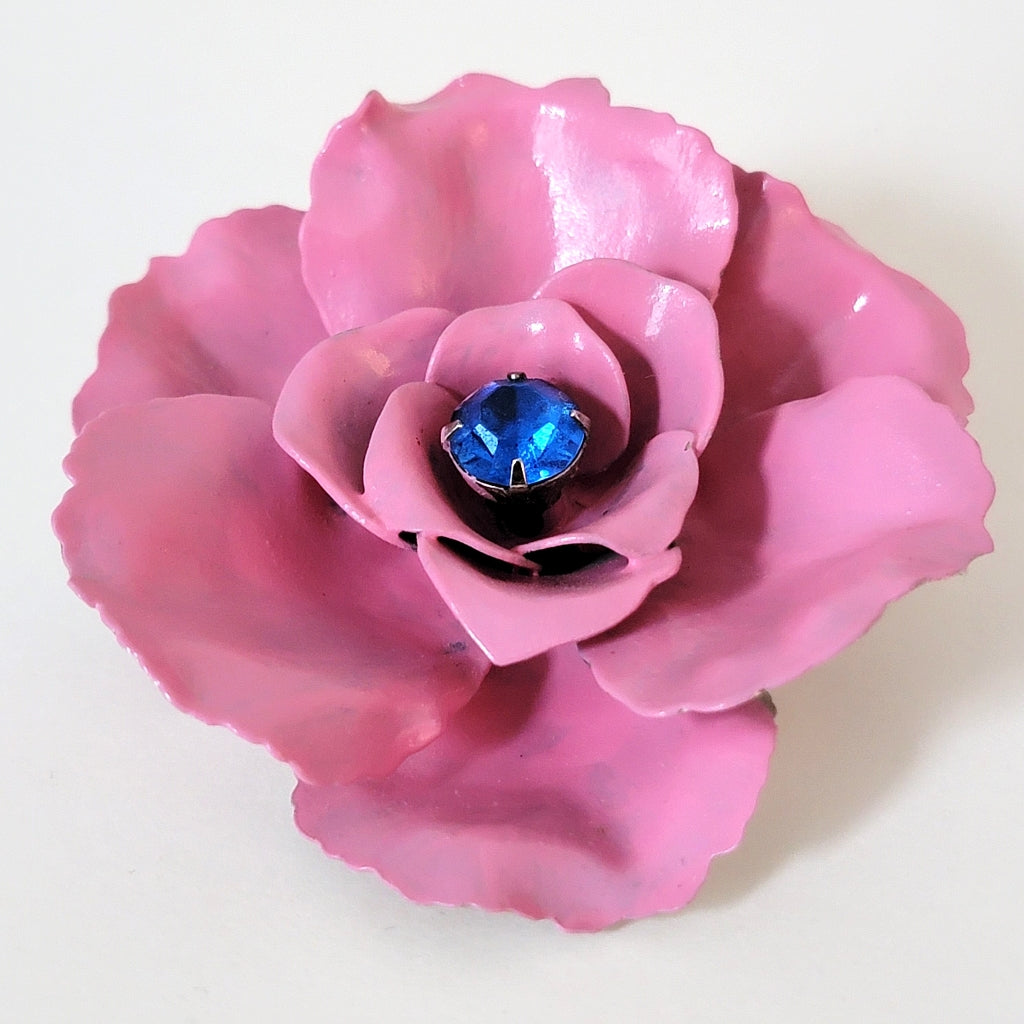 Pink enamel flower pin with layered petals.