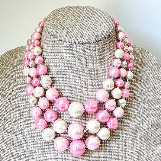 Pink three strand beaded necklace on display.