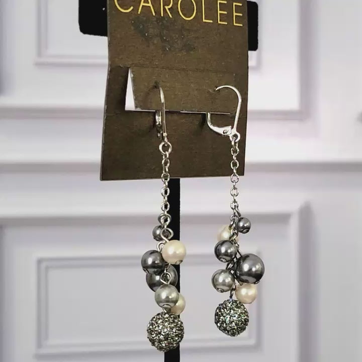 Long rhinestone and faux pearl dangle earrings on display stand.