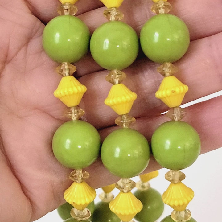 Green and yellow beaded necklace in hand.