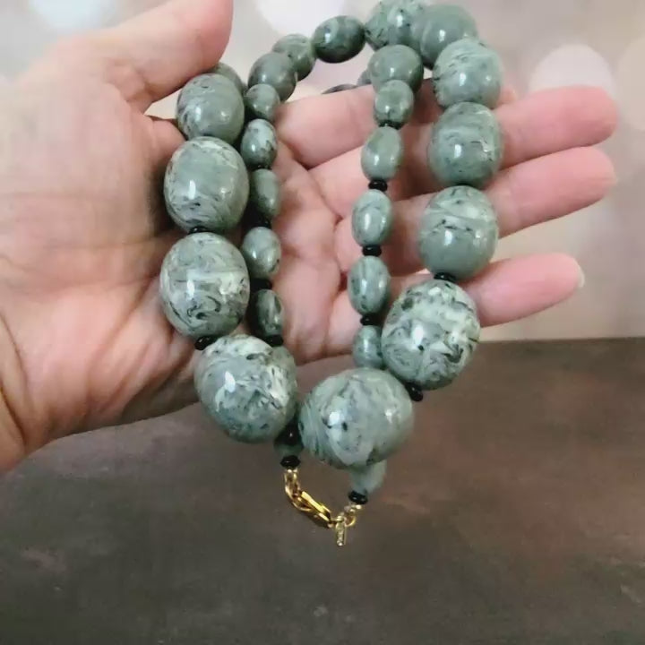 Gray chunky plastic beaded necklace in hand.