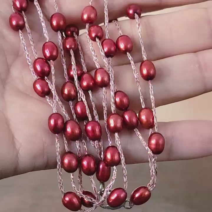 Red pearl beaded necklace in hand.