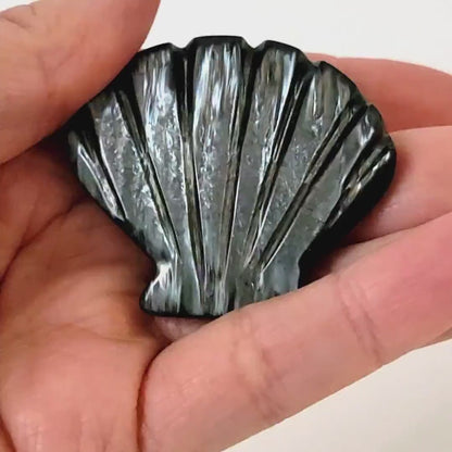 Vintage gray iridescent plastic shell brooch in hand.