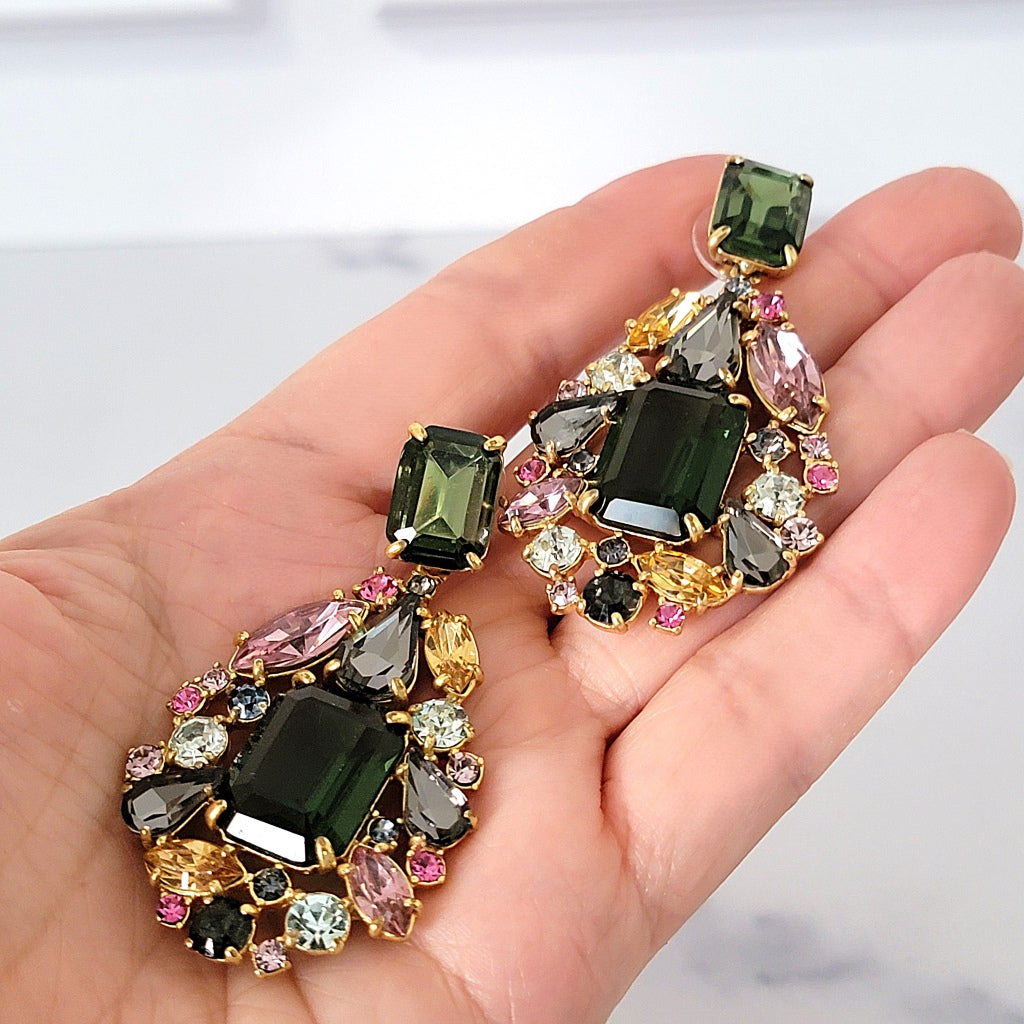 Big chunky rhinestone earrings in hand.