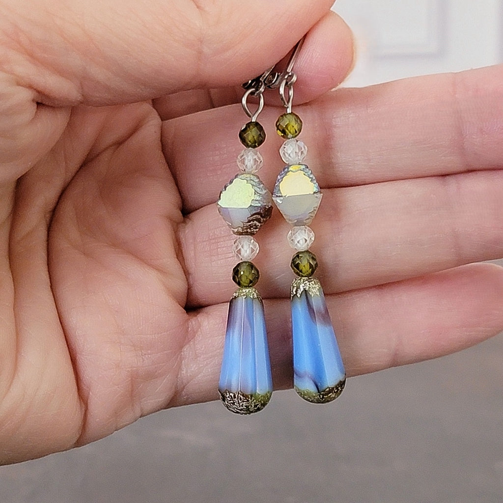 Blue dangle earrings in hand.