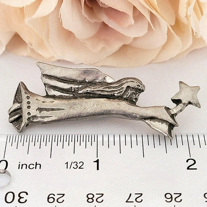 Angel brooch next to a ruler.