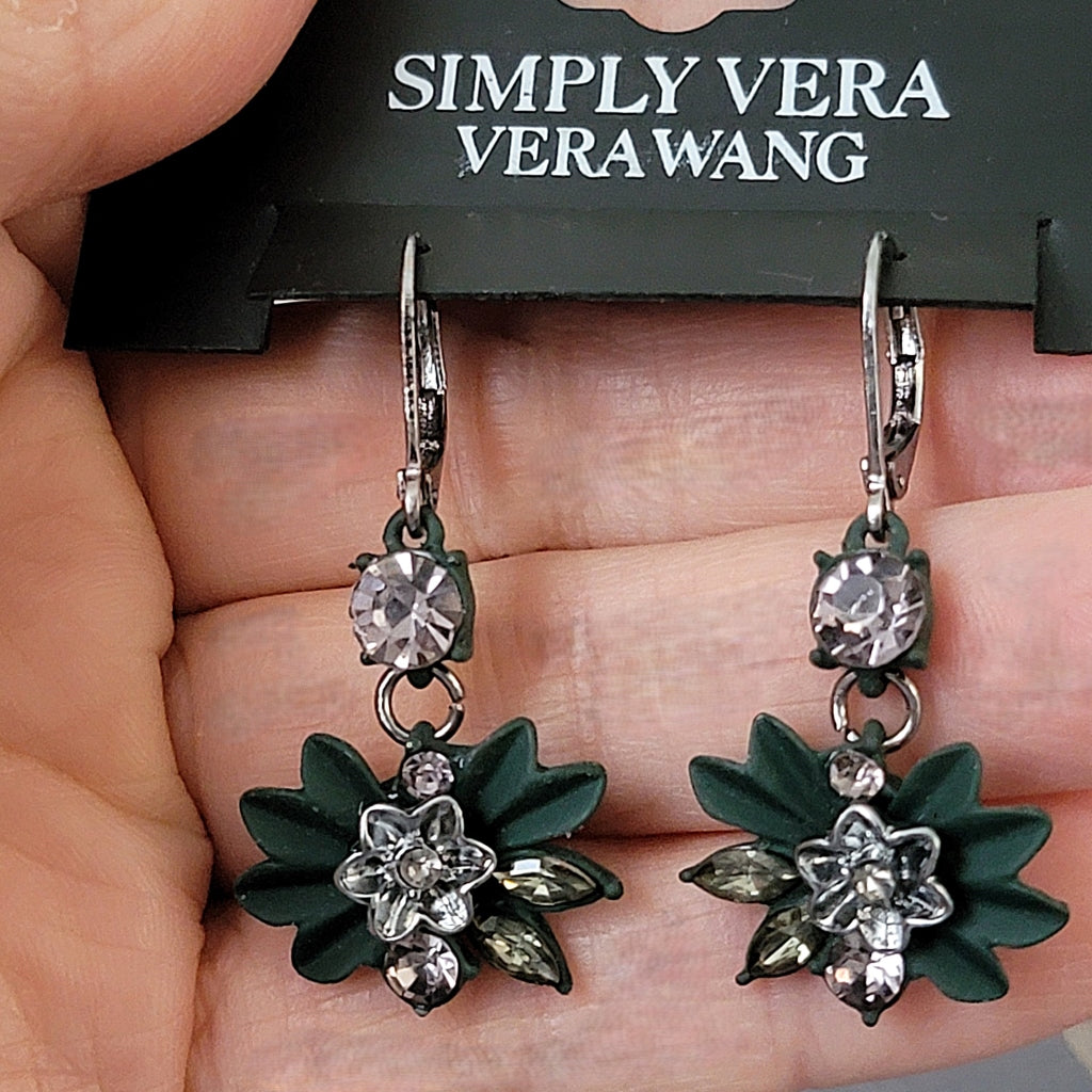 Green floral earrings in hand.