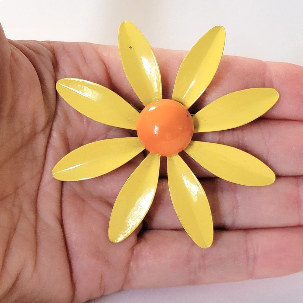 Yellow flower pin in hand.