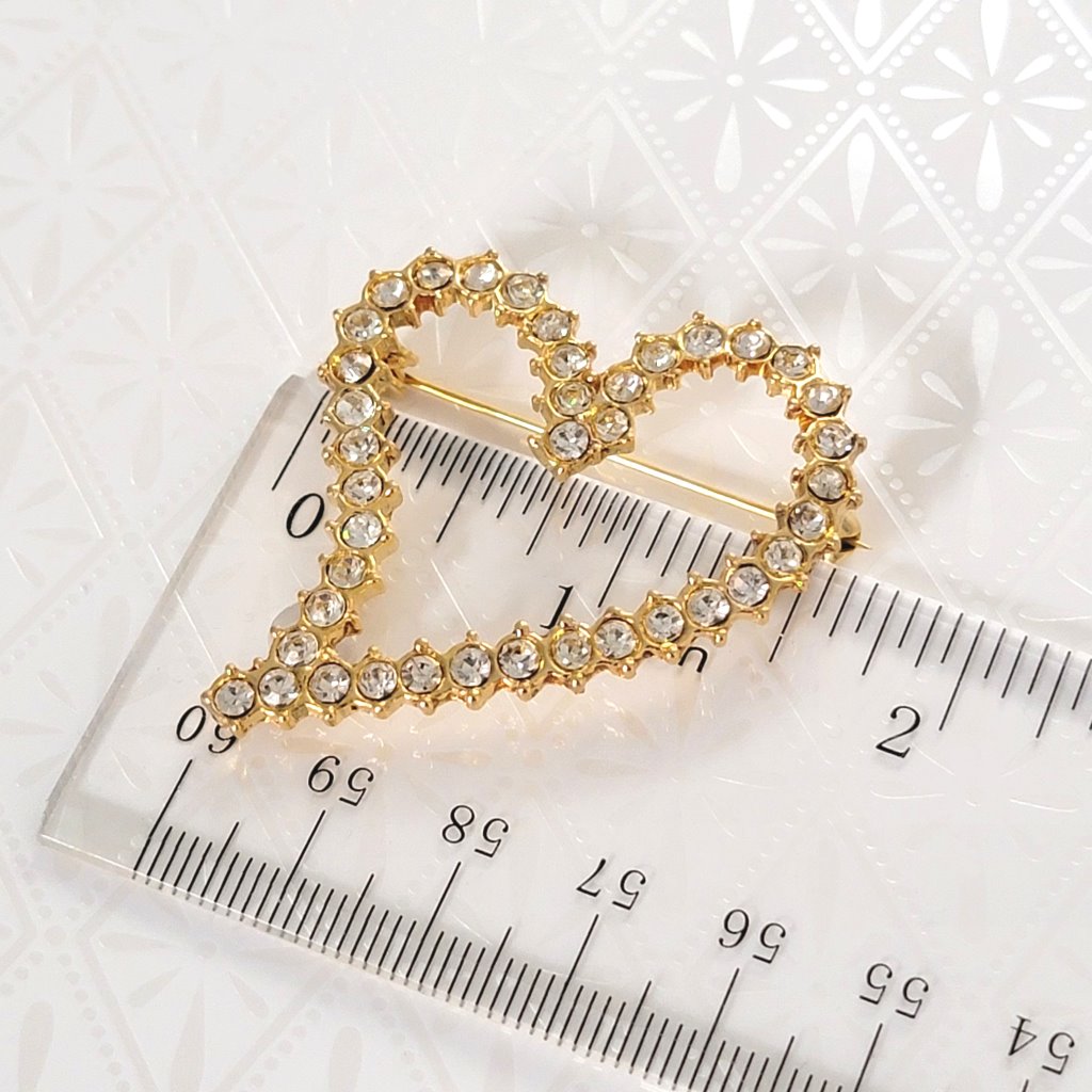 Vintage rhinestone heart brooch, next to a ruler.