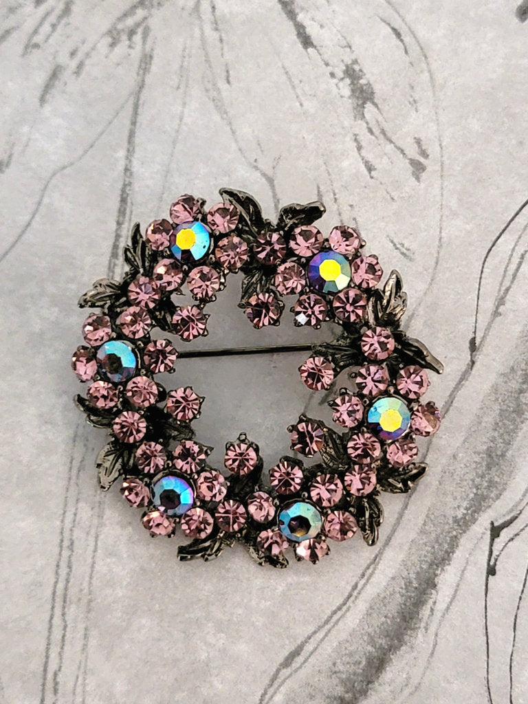 purple rhinestone brooch, with gunmetal color leaves, in a wreath shaped setting.