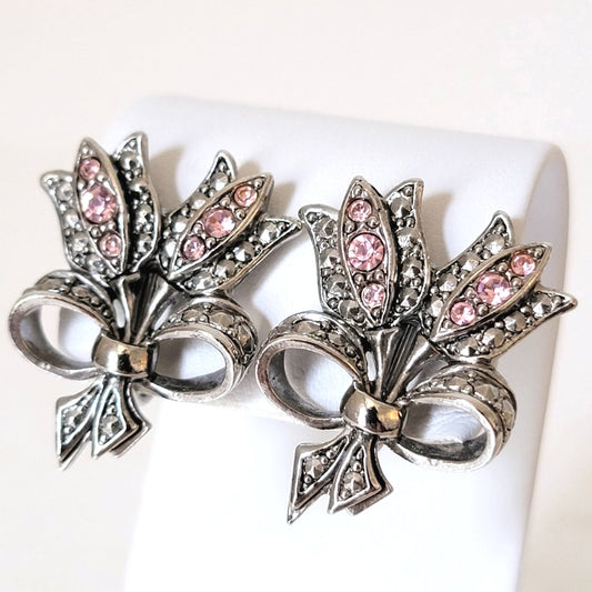 Vintage rhinestone Avon pink tulip clip earrings, shown on a display stand. Silver tone, faux marcasite, bow tied, bouquet style.